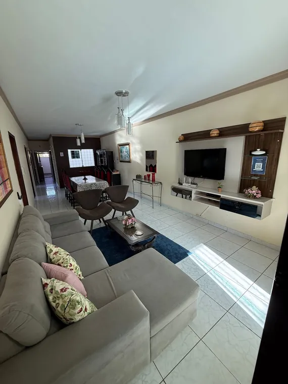 Sala de estar com sofá, televisão e mesa de jantar ao fundo