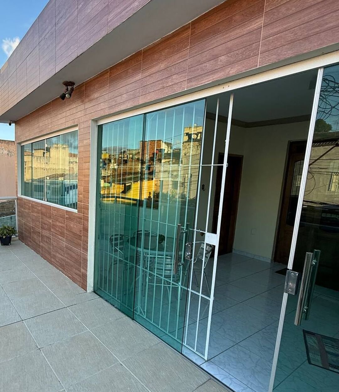 Varanda da Casa Matriz com piso claro e portas de vidro que dão acesso à sala
